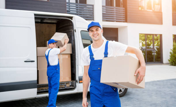 Two removal company workers unloading boxes from minibus into new home.
