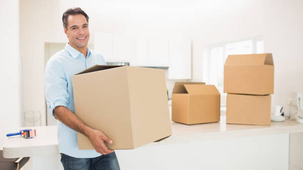Portrait of a smiling man carrying boxes in a new house