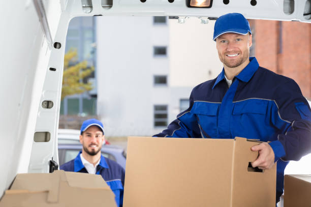 Smiling Young Male Mover Unloading Cardboard Box From Truck